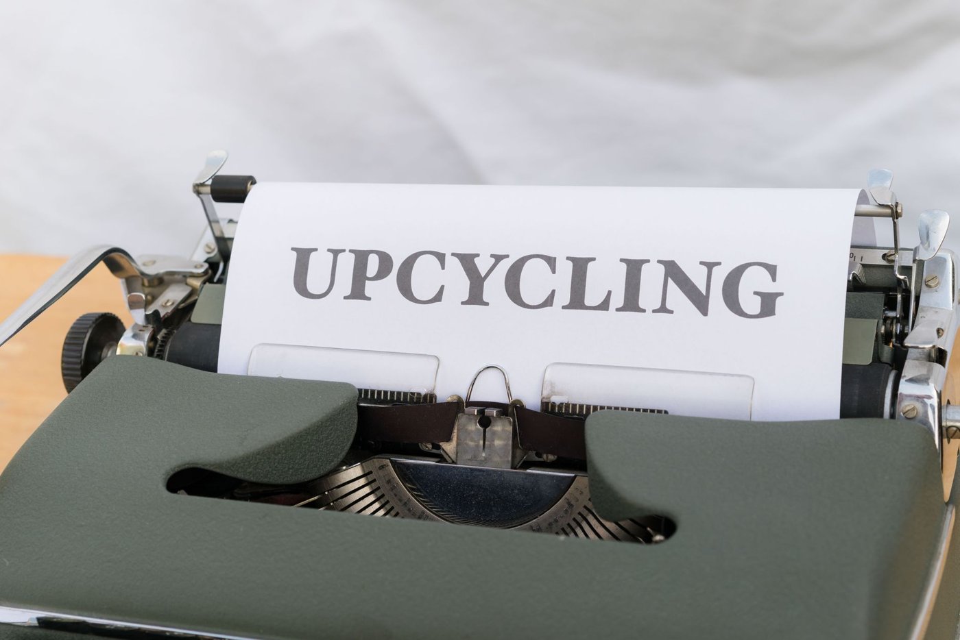 Yeşil renkli eski tip daktilo üzerinde beyaz kağıda büyük harflerle "UPCYCLING" kelimesi yazılı